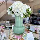 Mint green vase with white flowers on a decorated table