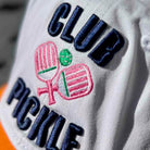 Close-up of a cap with 'Club Pickle' text and pickleball paddle design.