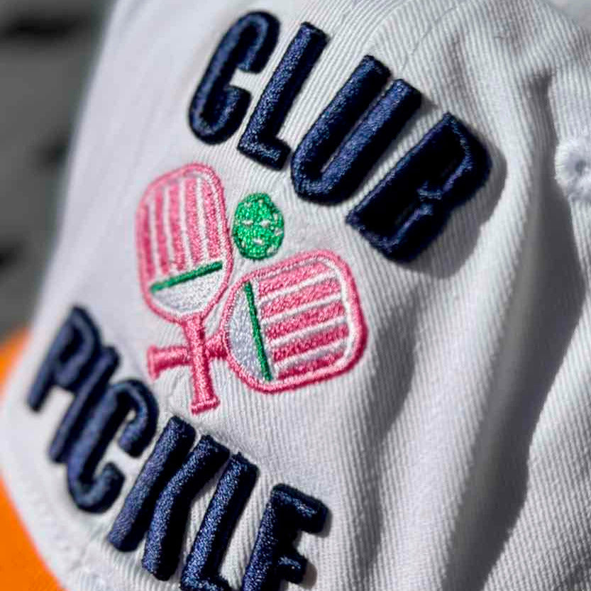 Close-up of a cap with 'Club Pickle' text and pickleball paddle design.