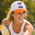 Woman wearing a 'Club Pickle' cap holding a pickleball paddle on a blurred green background