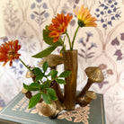 Decorative vase shaped like mushrooms with flowers on a book against a patterned background