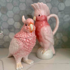 Two ceramic parrot figurines on a tiled surface with a hexagonal tile pattern.