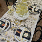 Dining table set with place settings, glasses, and a decorative tablecloth.