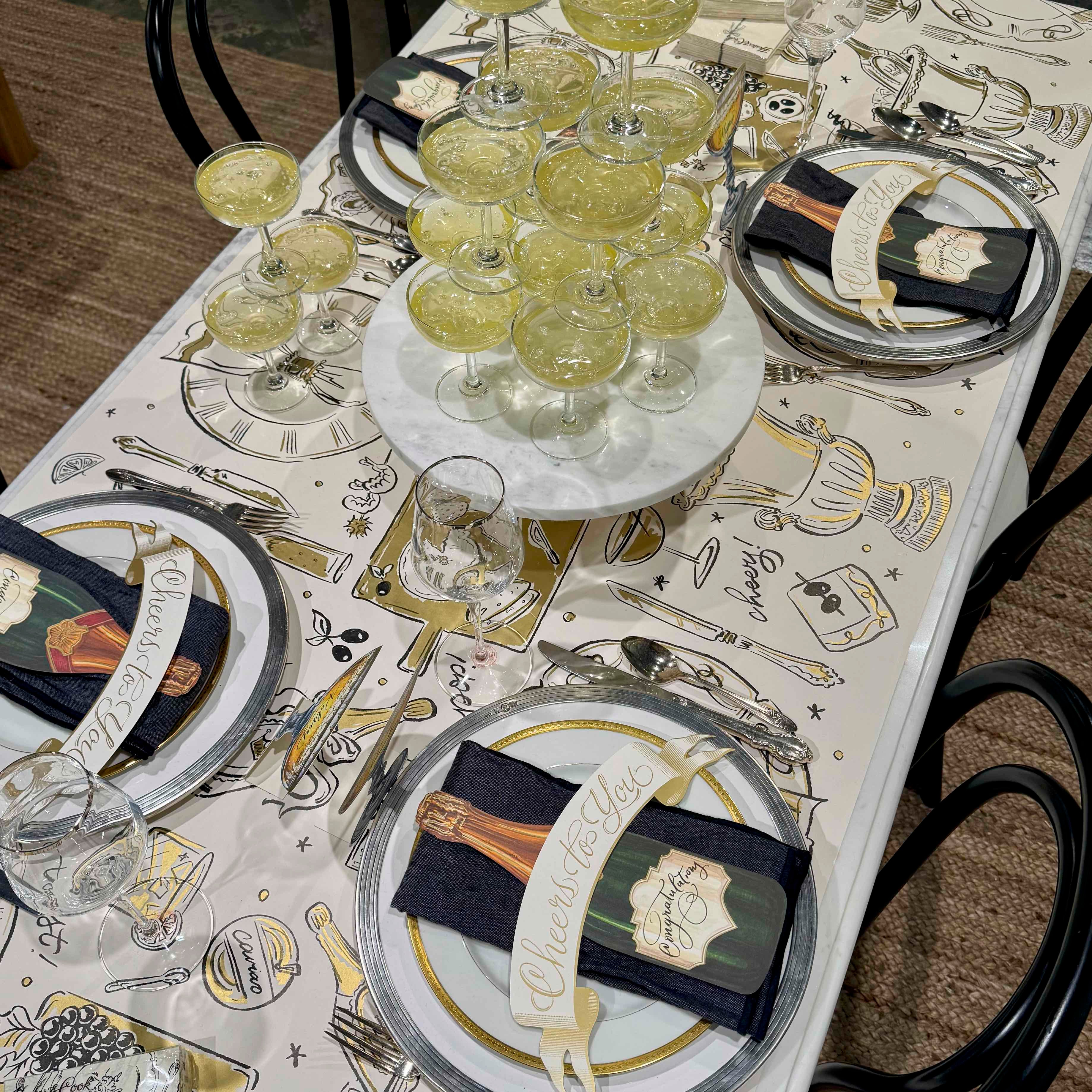 Dining table set with place settings, glasses, and a decorative tablecloth.