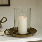 Candle in a glass holder on a metal tray with a white background