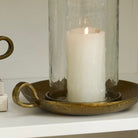Candle in a glass holder on a decorative tray with a white background