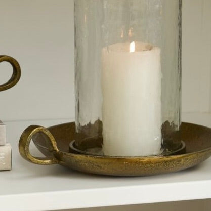Candle in a glass holder on a decorative tray with a white background