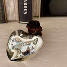 Heart-shaped decorative object with a rose on a textured surface