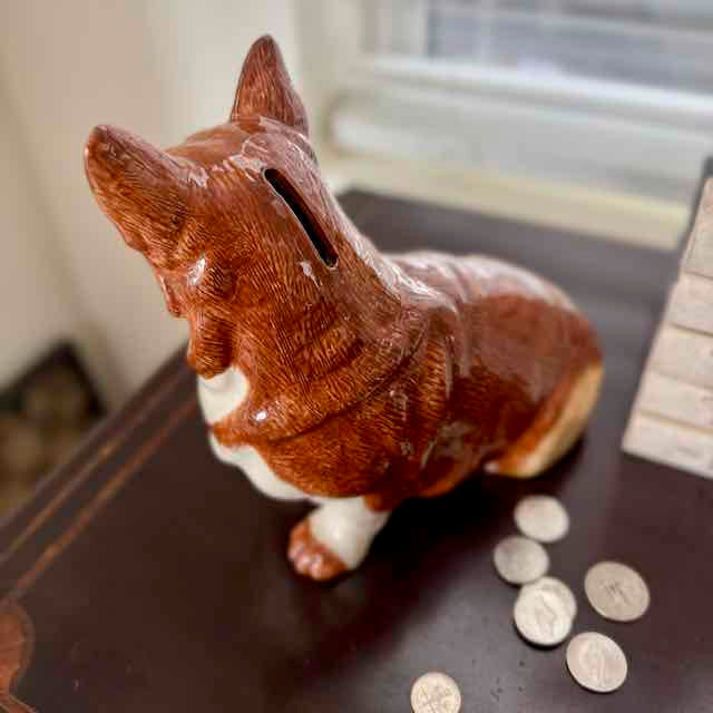 Dog-shaped piggy bank with coins on a wooden surface