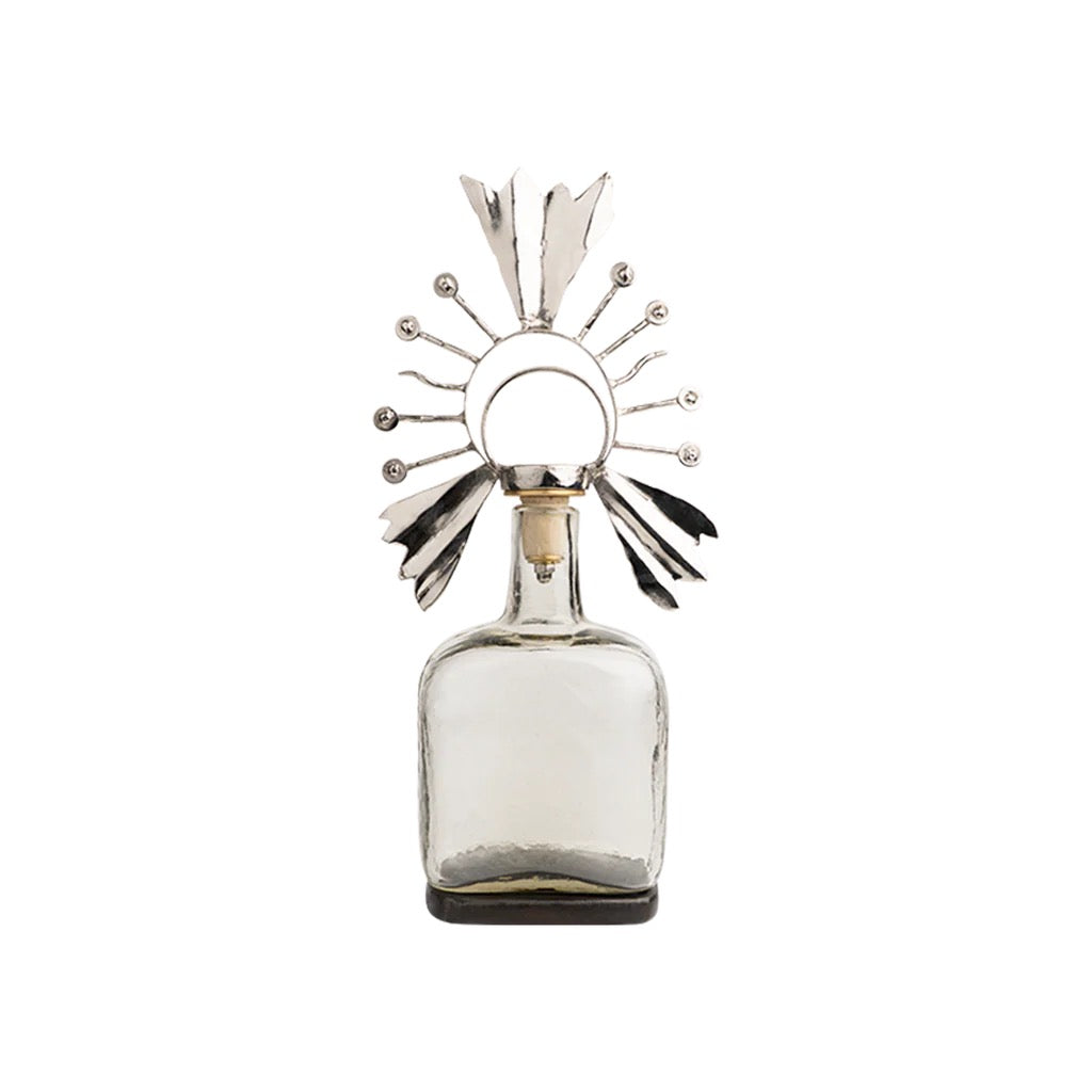 Decorative glass bottle with a metallic sunburst top on a white background