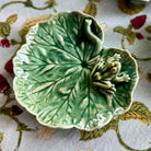 Green ceramic leaf-shaped dish with a frog on a patterned fabric background
