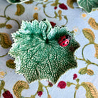 Decorative ceramic leaf with a ladybug on a floral-patterned fabric background