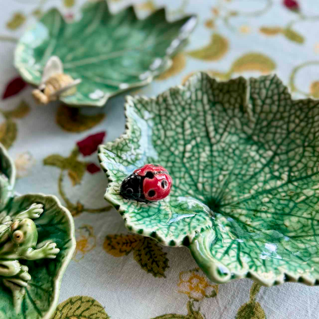 Ceramic leaf-shaped dish with a ladybug design on a floral fabric background