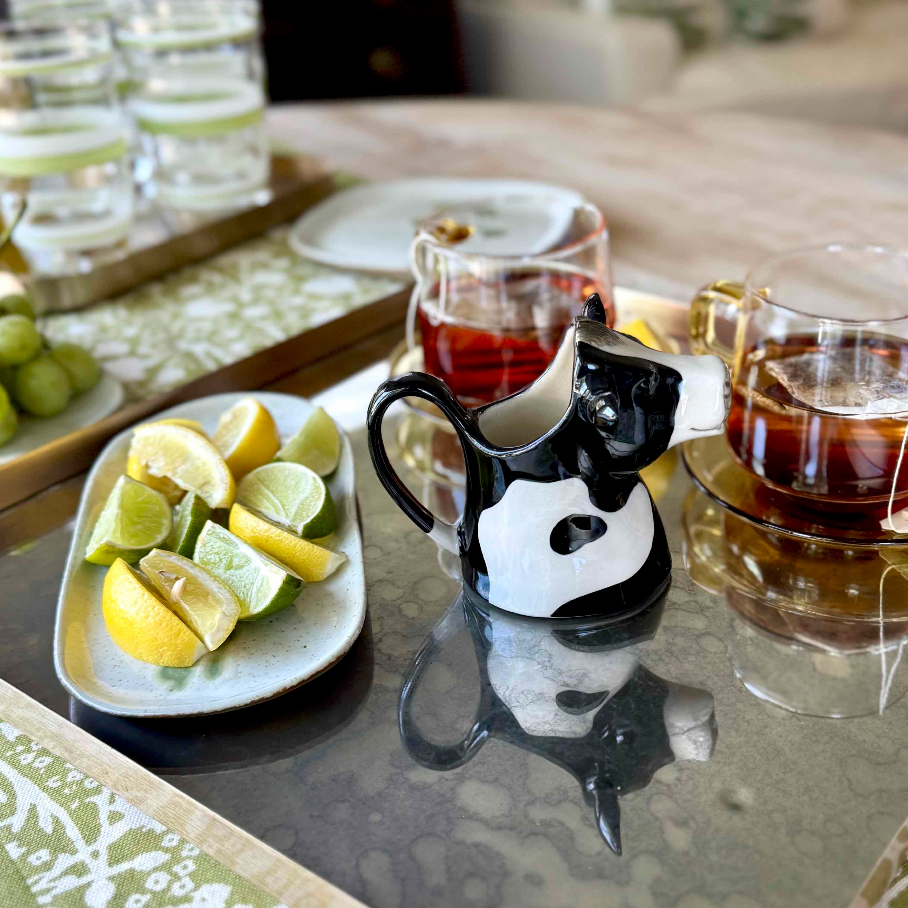 Cat-shaped ceramic pitcher on a table with lemons and limes