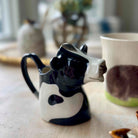 Ceramic cow-shaped creamer on a wooden surface with a blurred background