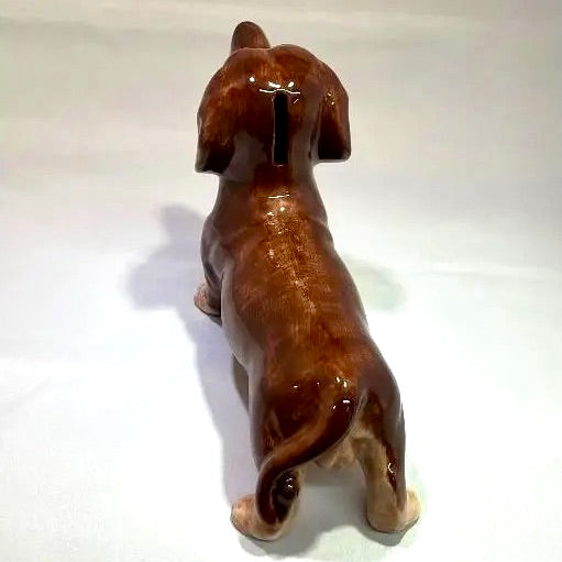 A glossy brown ceramic dachshund figurine shown from behind on a plain white background.
