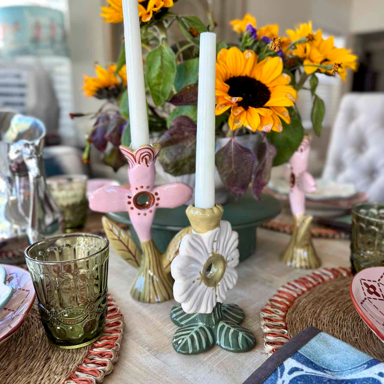 Decorative table setting with sunflowers, candle holders, and a glass on a table.