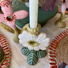 Decorative ceramic candle holder with a white candle on a table with other decorative items.
