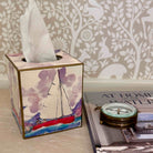 Tissue box with sailboat design on a surface with a decorative background