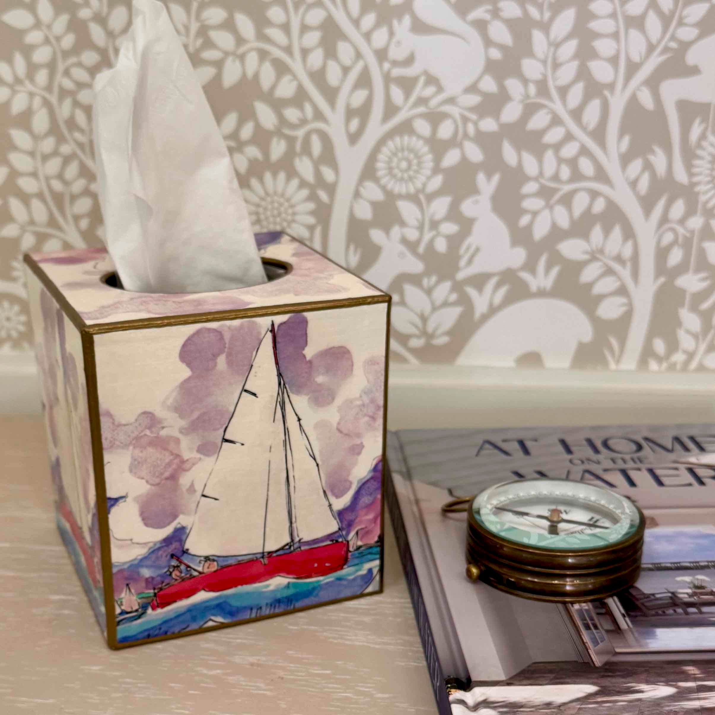 Tissue box with sailboat design on a surface with a decorative background