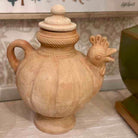 Decorative terracotta vase shaped like a chicken on a marble surface.