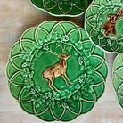 Decorative green plates with deer and floral designs on a wooden surface