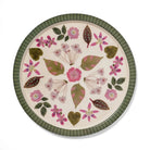 Round ceramic plate with floral and leaf pattern on a white background