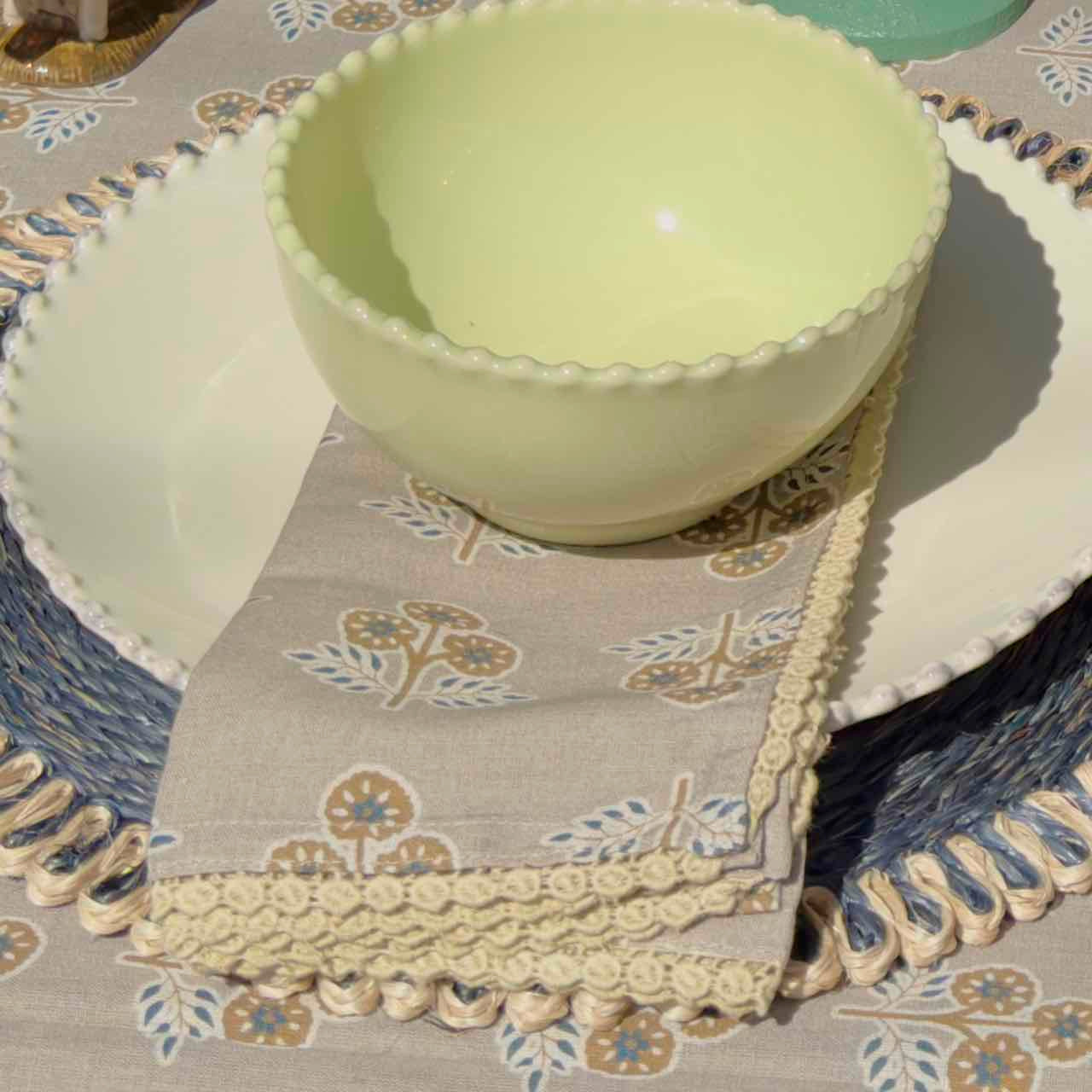 Light green bowl on a decorative tablecloth with floral patterns