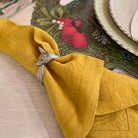Yellow napkin with a silver fox-shaped napkin ring on a decorative table setting.