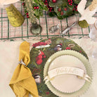 Decorative table setting with a green plate featuring nature-themed design, yellow napkin, and festive decorations.