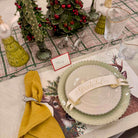 Christmas-themed table setting with plates, napkin, and decorative elements on a patterned tablecloth.