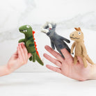 Three small plush toys held in hands against a light background