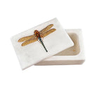 A small rectangular white stone box with its lid leaning against the base, featuring a detailed dragonfly illustration on the lid in warm brown, gold, and blue tones.