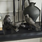 Decorative bird statues on a shelf with a vase in the background