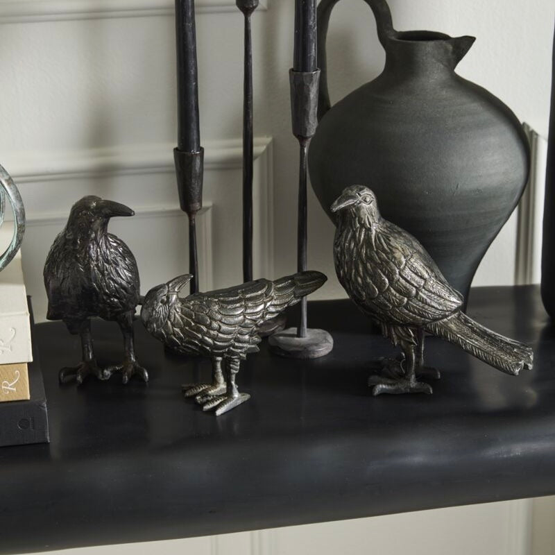 Decorative bird statues on a shelf with a vase in the background