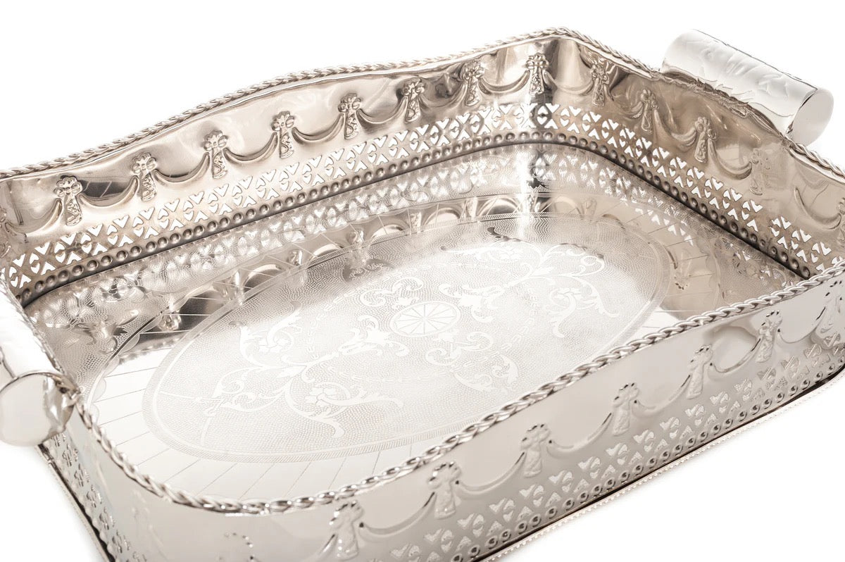 Silver decorative tray with intricate patterns on a white background
