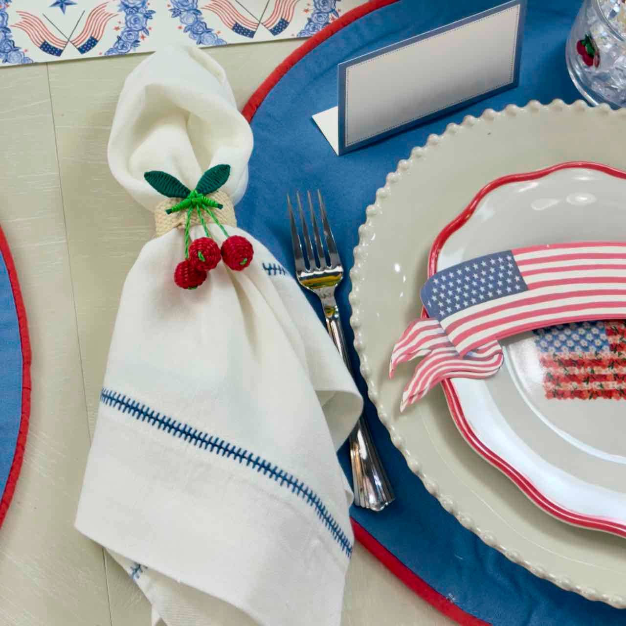 Table setting with American flag-themed plates and a napkin with cherry decorations.