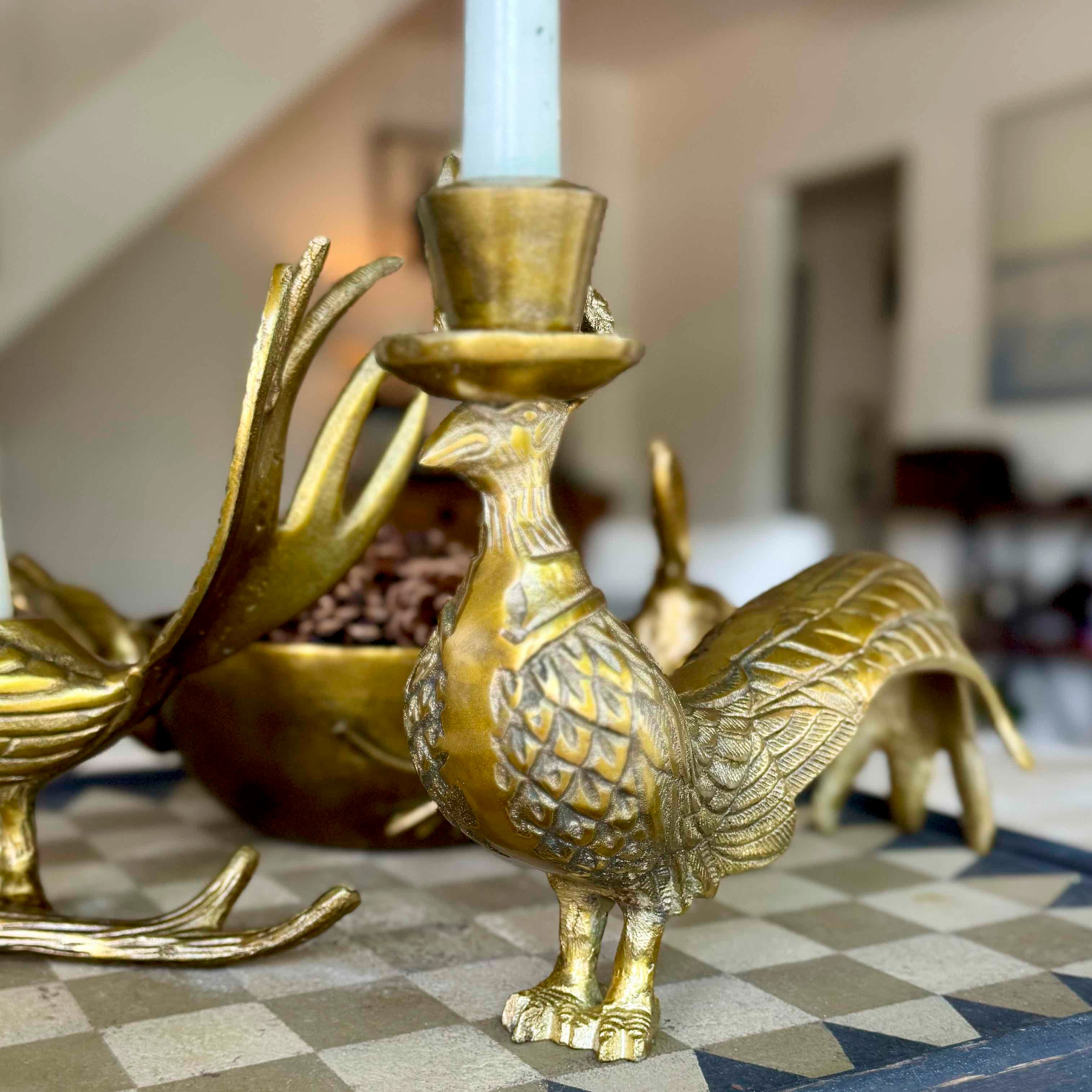 Gold bird-shaped candle holder with a candle on a checkered floor.