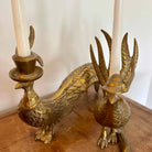 Brass peacock-shaped candle holder with candles on a wooden surface.