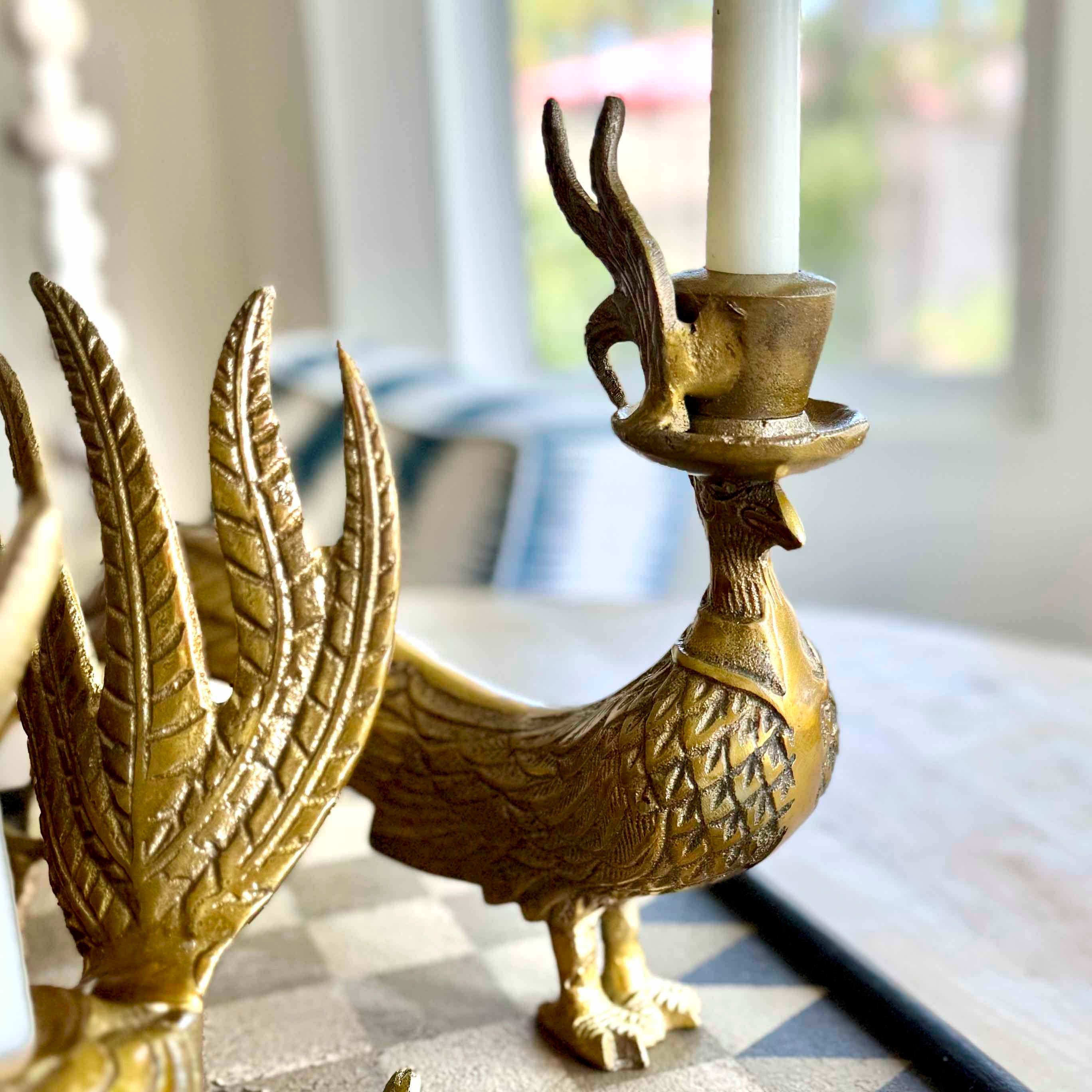 Gold bird-shaped candle holder with a candle on a surface.