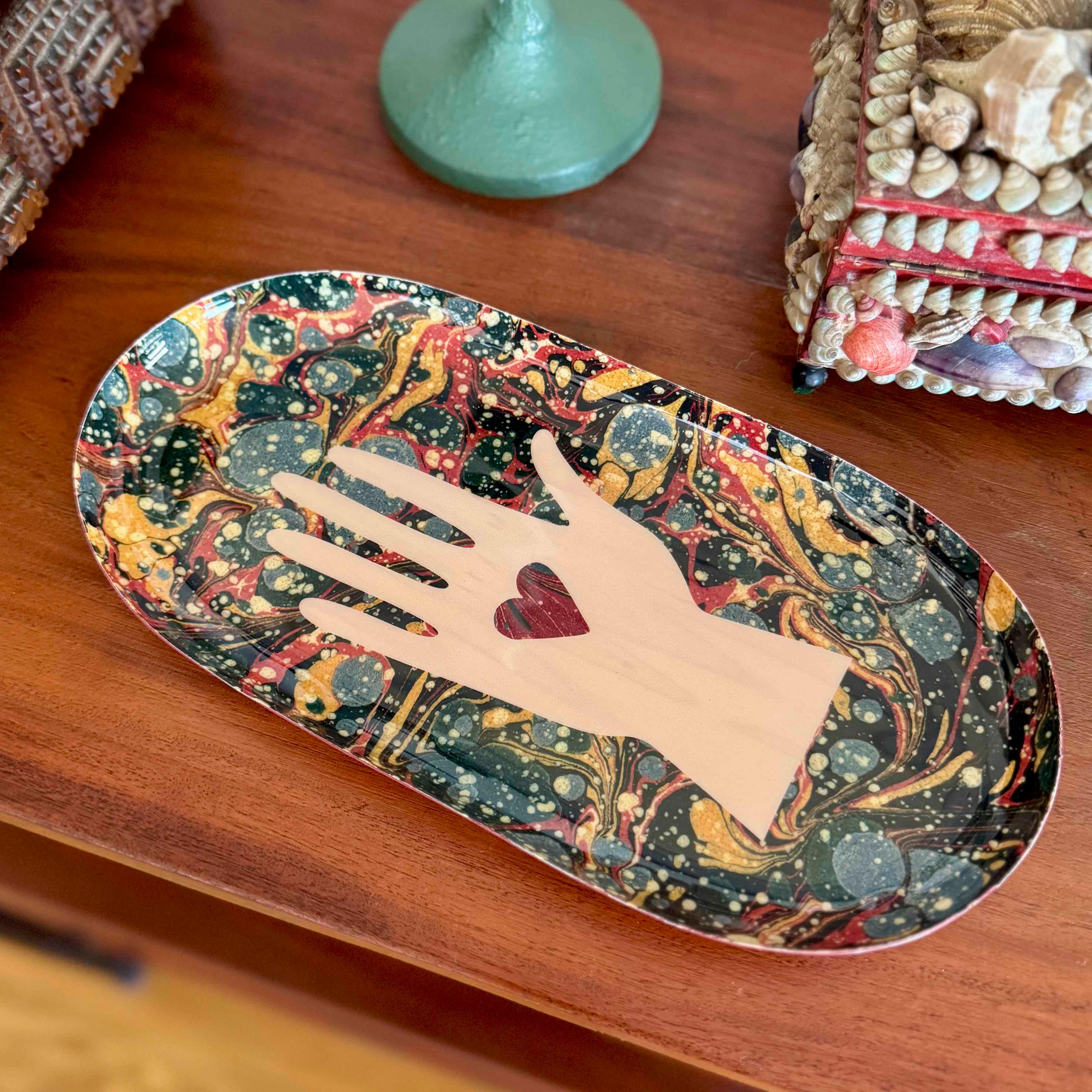 Decorative tray with hand and heart design on a wooden surface