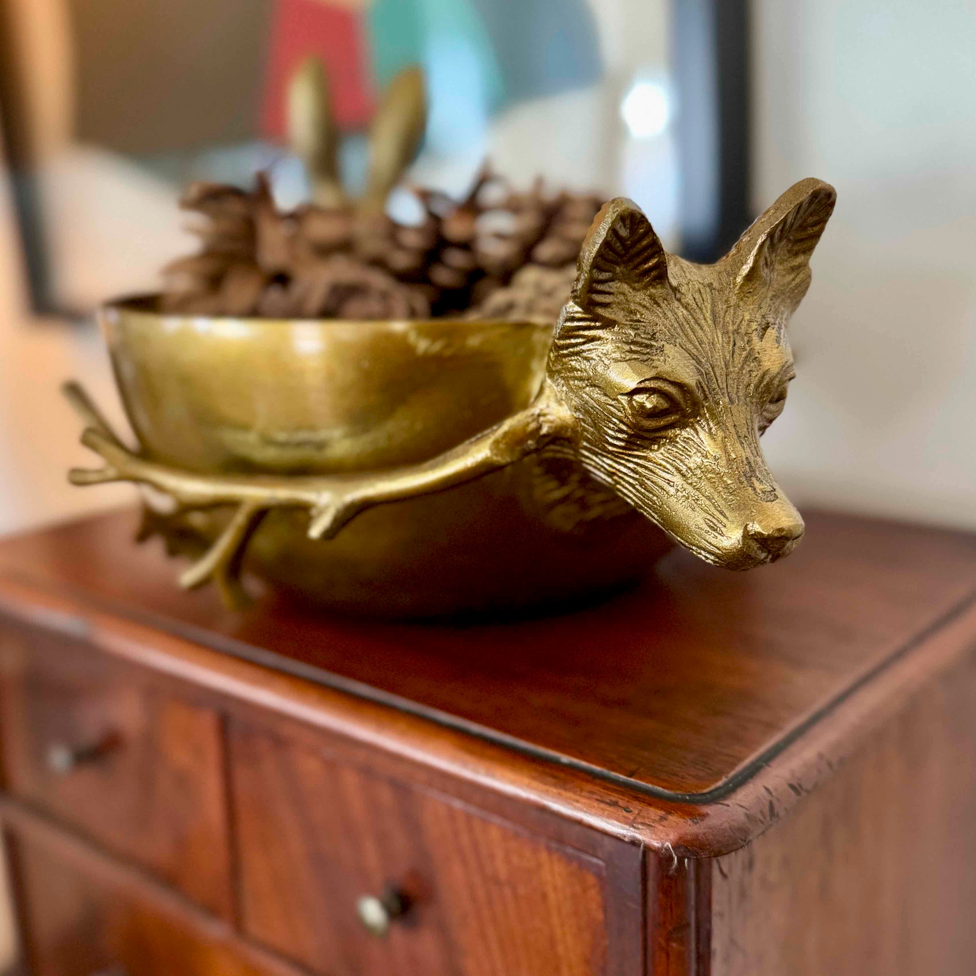 Gold fox-shaped bowl on a wooden surface with blurred background