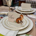 Table setting with decorative plates and a card featuring a fox illustration.