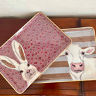 Two decorative trays with animal illustrations on a wooden surface.