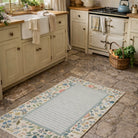 Floral patterned rug on a stone floor in a kitchen with vintage-style cabinets and appliances.