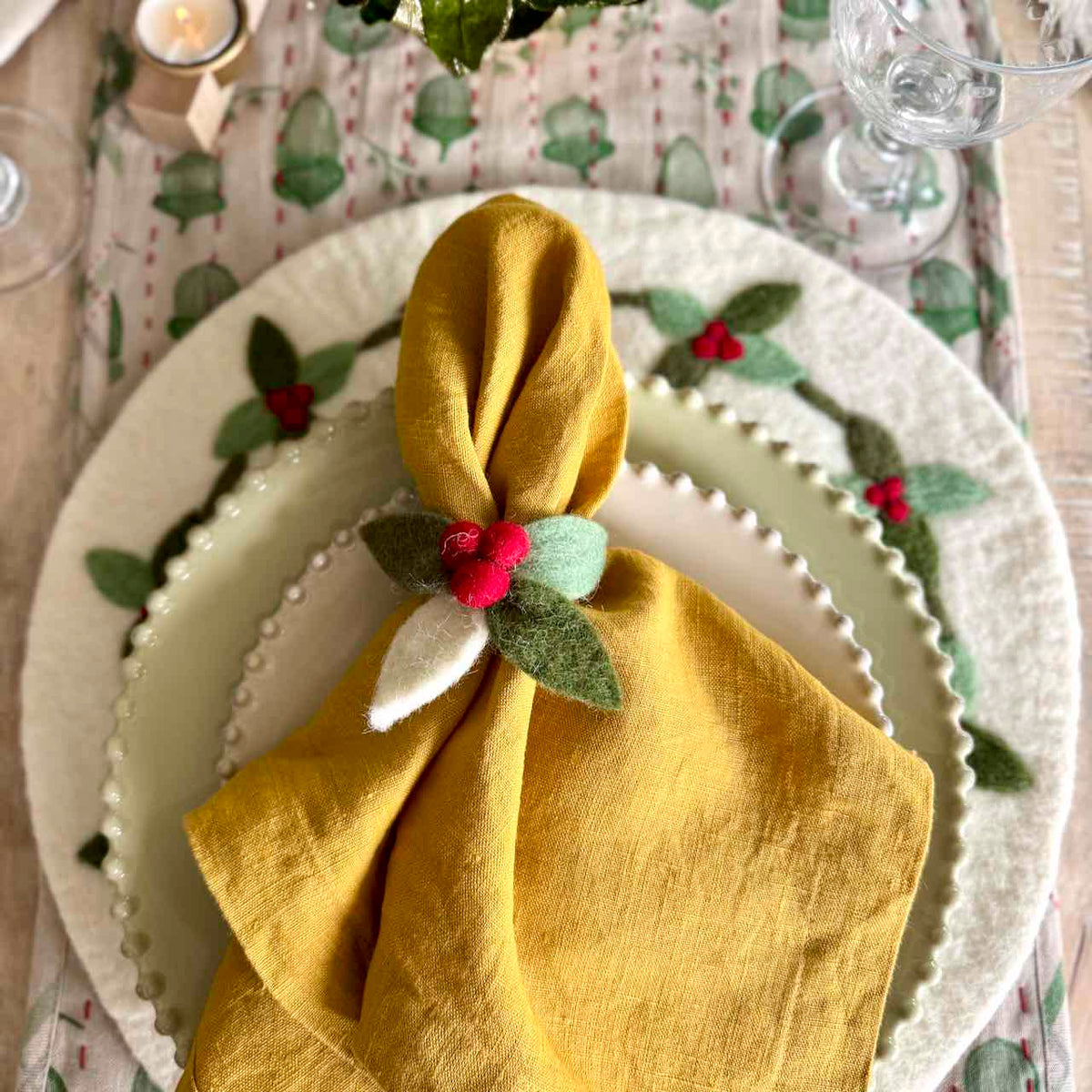 Yellow napkin with a decorative flower on a Christmas-themed table setting.