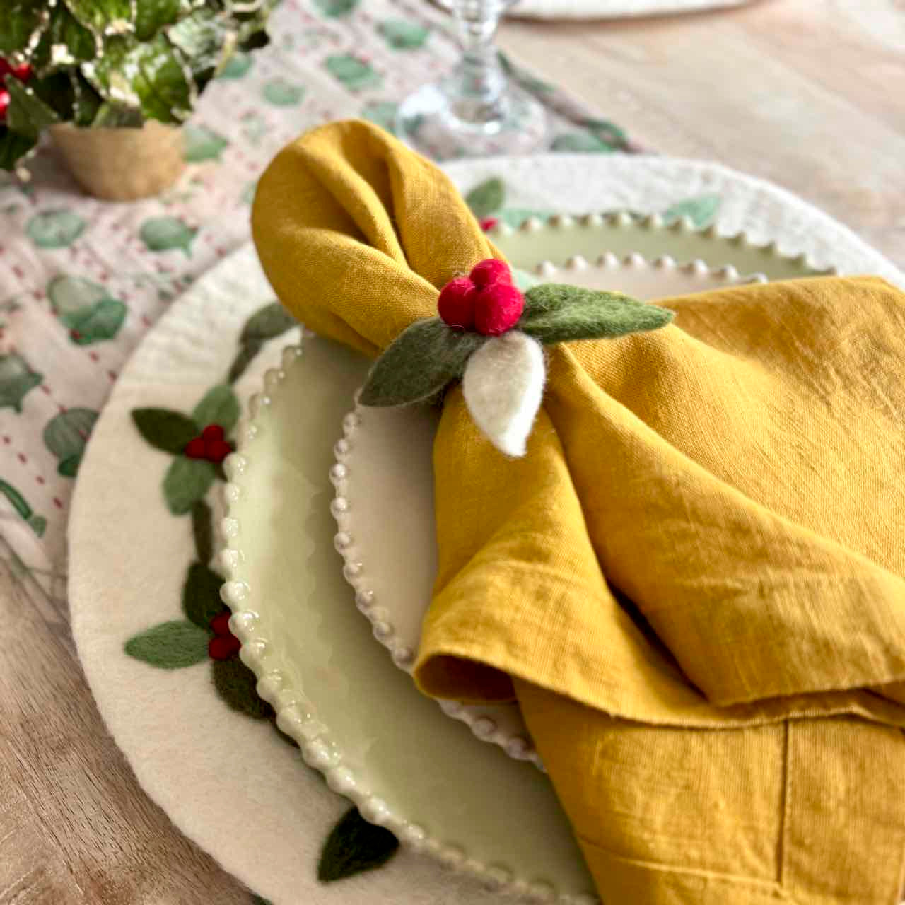 Yellow napkin with decorative flower on a plate with a floral tablecloth.