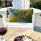 Decorative pillow on a white chair with a glass of red wine and plate of snacks on a table.