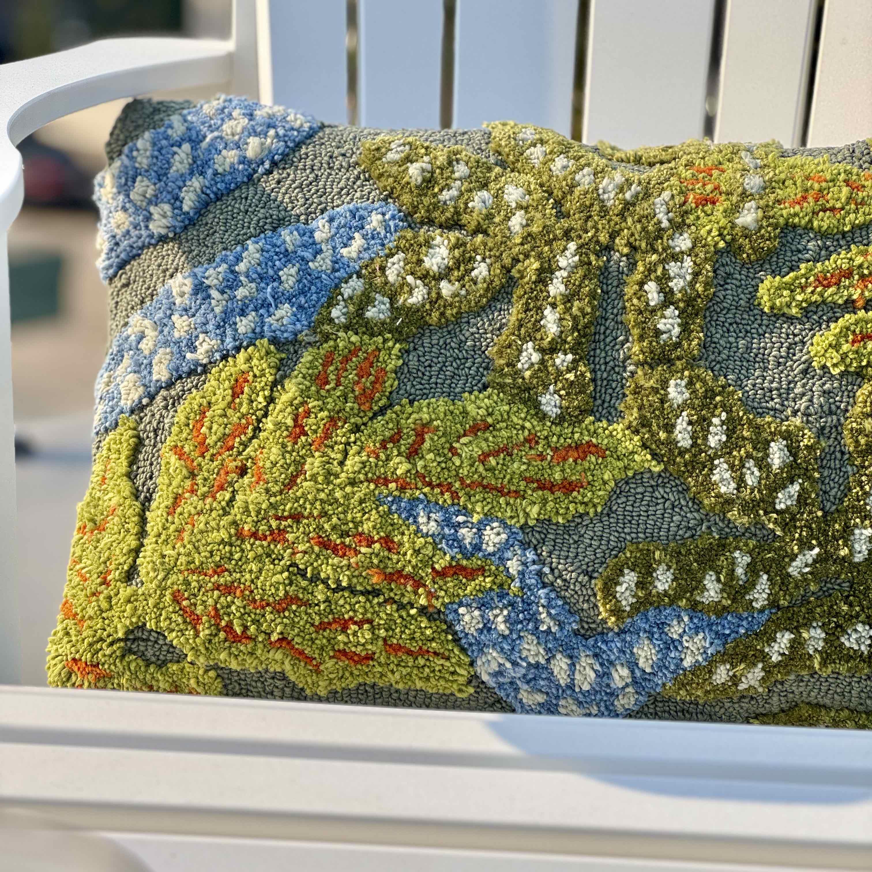 Decorative pillow with nature-themed pattern on a white chair