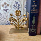 Gold floral bookend on a wooden surface with books in the background